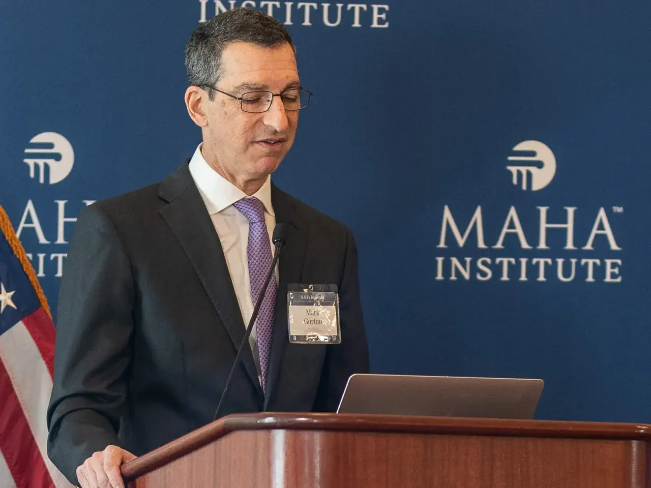 MAHA Institute leader speaking from the podium in front of MAHA Institute backdrop