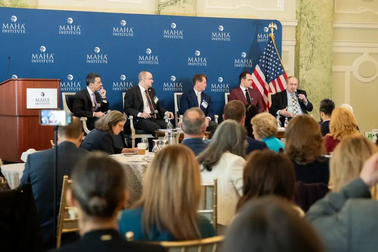 Panel discussion in front of MAHA Institute branded backdrop with an engaged audience